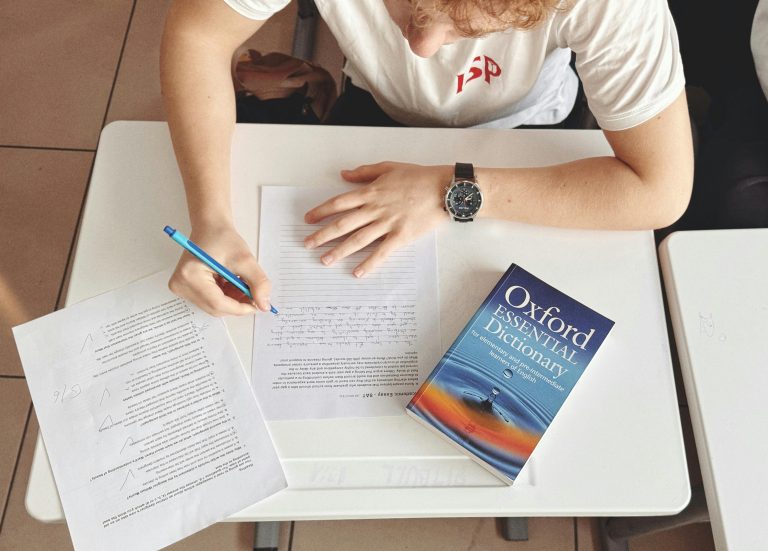 A young boy taking an English test with an Oxford dictionary on his table